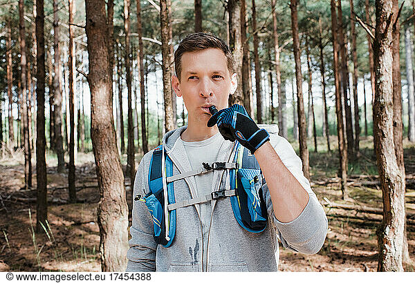 man drinking from a bladder in his running vest whilst in the forest