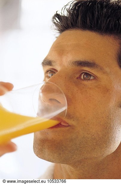 Man drinking glass of orange juice