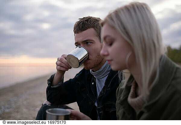 Man drinking tea near girlfriend in countryside