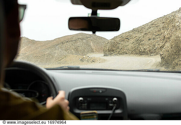 Man driving a car on a mountain road of the desert. Road trip.