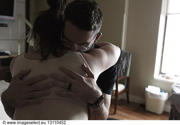 Man embracing pregnant woman in hospital ward