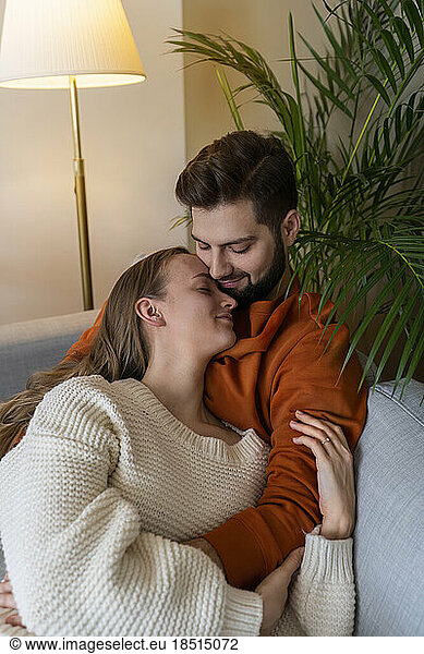 Man embracing woman on sofa at home