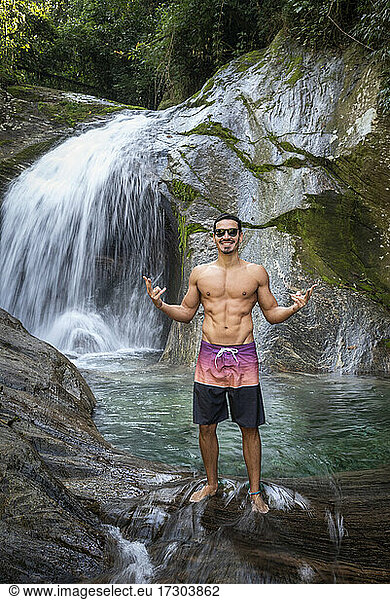 Man enjoying beautiful crystal clear water rainforest waterfall