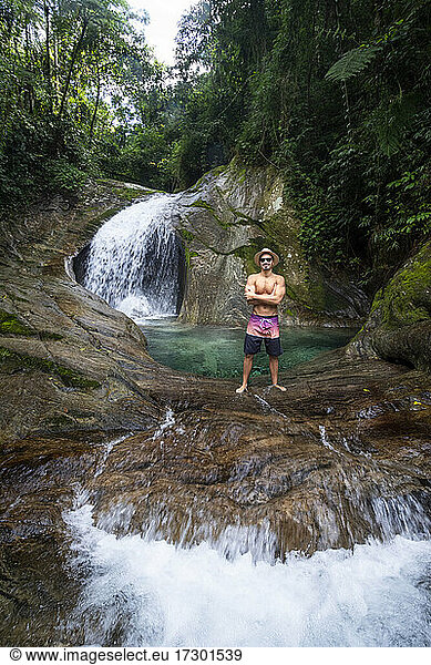 Man enjoying beautiful crystal clear water rainforest waterfall pool