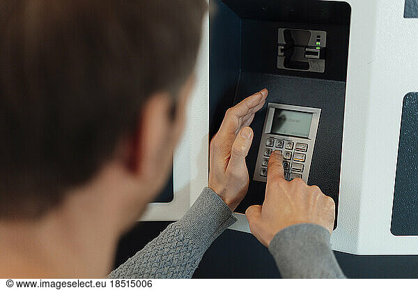 Man entering pin in ATM machine