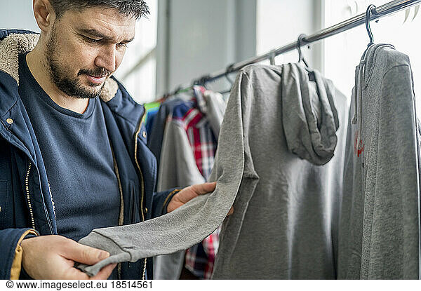Man examining gray hoodie in clothes store