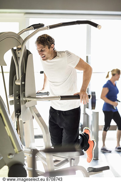 Man exercising on pull-up assist machine at gym