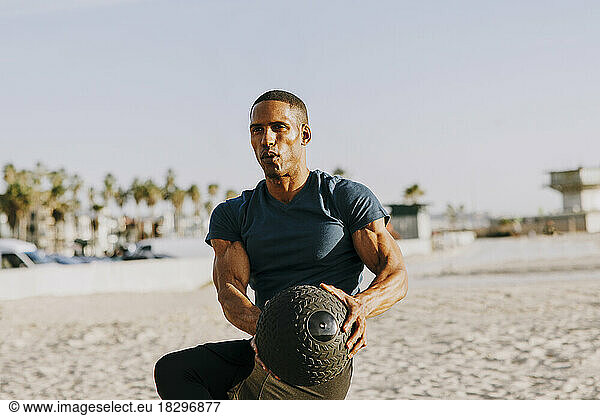 Man exercising with medicine ball on beach