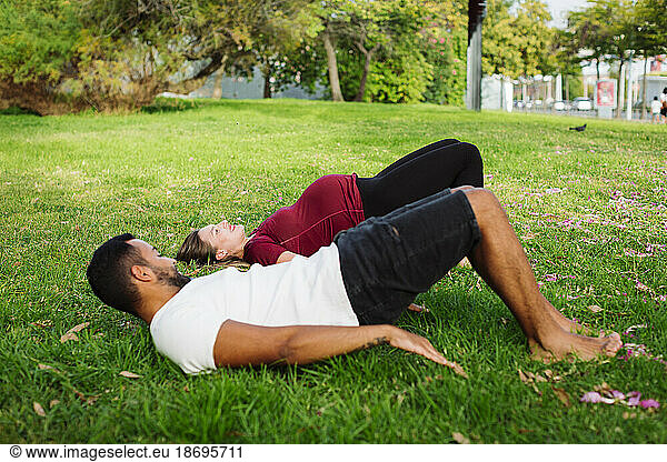 Man exercising with pregnant woman lying on grass