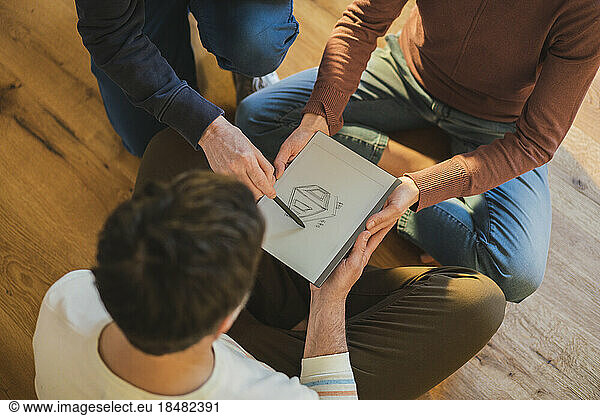 Man explaining house blueprint on paper to couple sitting at home