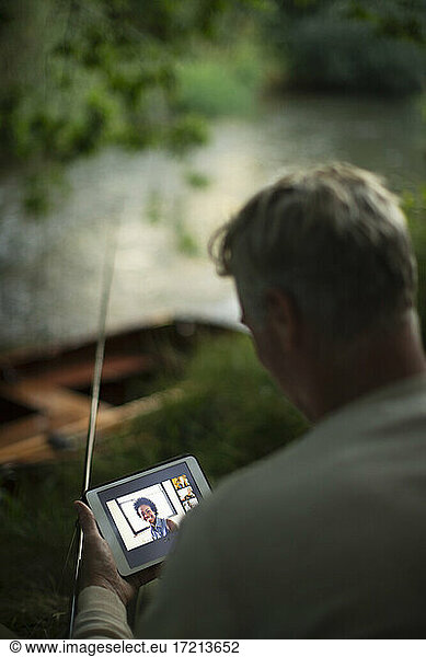 Man fly fishing and video chatting with digital tablet