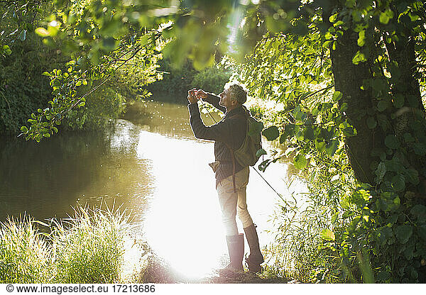 Man fly fishing at sunny idyllic summer river