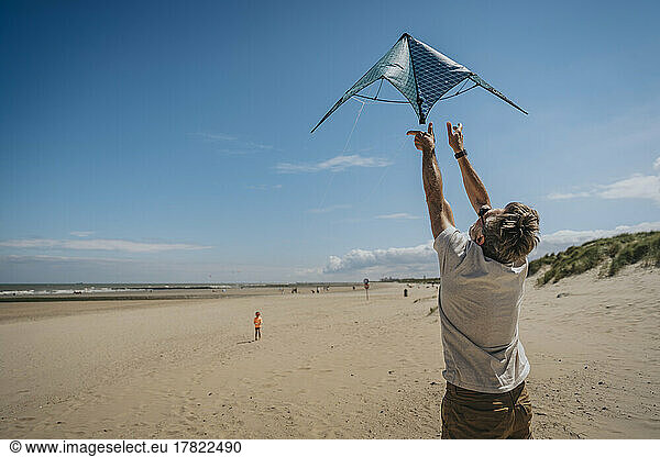 Man flying kite on sunny day at beach
