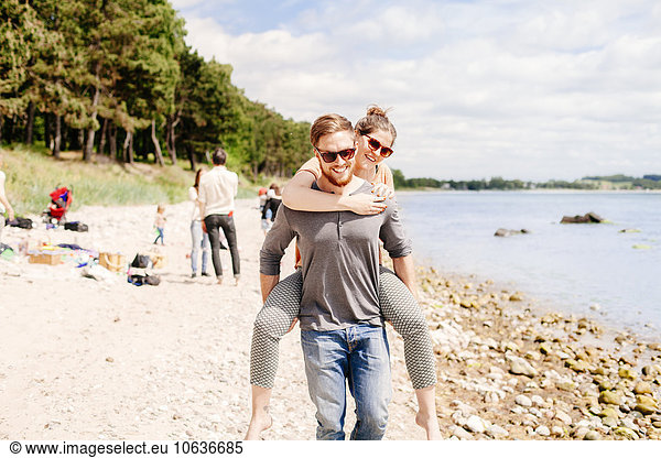 Man giving girlfriend piggyback ride on beach