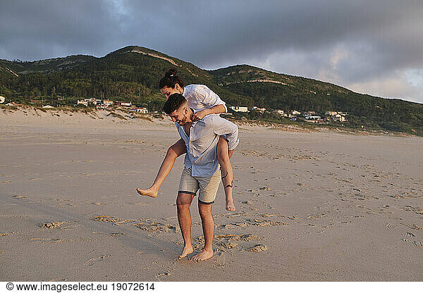 Man giving piggyback ride to woman at beach