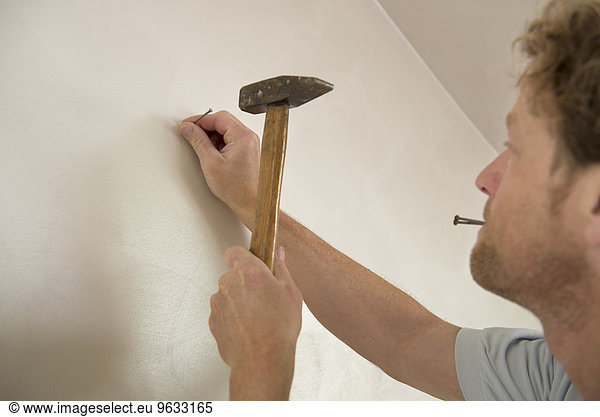 Man hammer nail wall portrait close-up