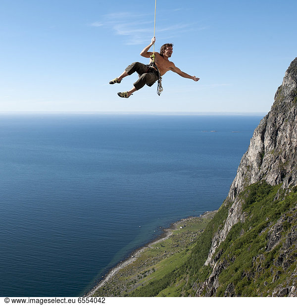 Man hanging on rope while climbing