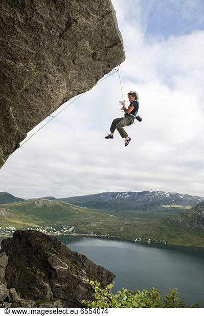 Man hanging on rope while climbing