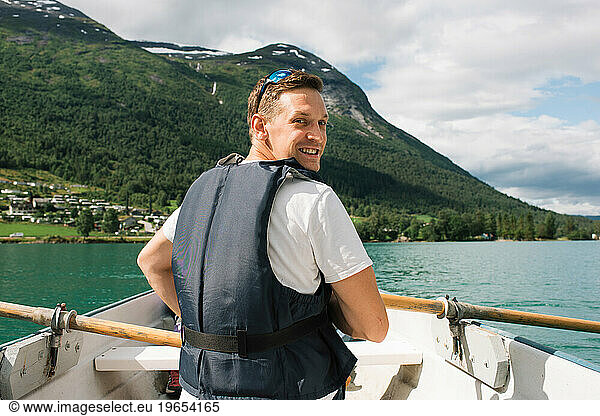 man happily rowing a boat in a Norwegian Fjord