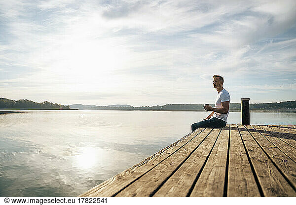 Man having coffee on pier by lake