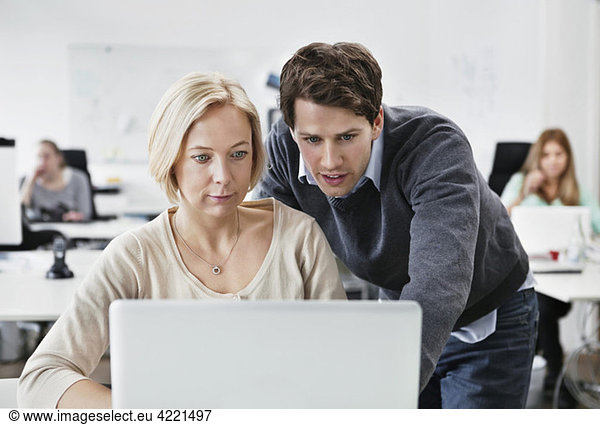 Man helping colleague with computer