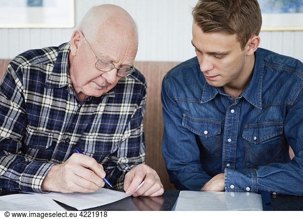 Man helping senior to fill in a form