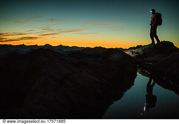 Man hiking on mountain summit at night with headlamp.
