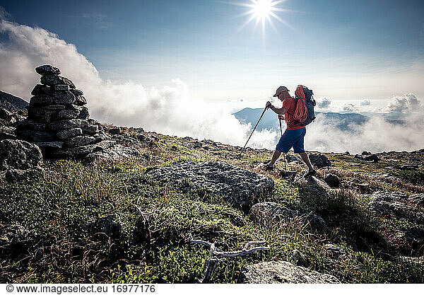 Man hiking through mountains with backpack and hiking poles