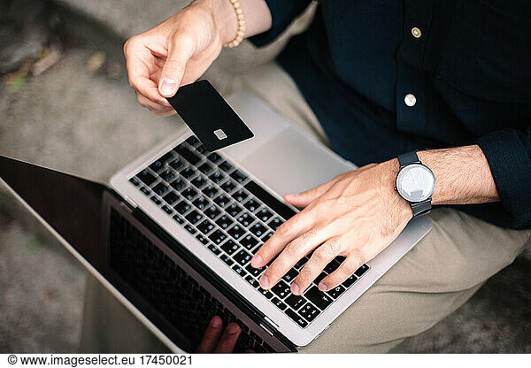 Man holding credit card using laptop computer doing online shopping