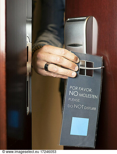 Man holding do not disturb sign label at hotel door