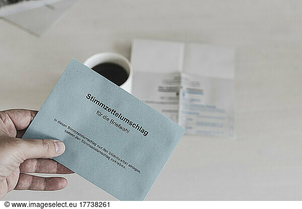 Man holding German ballot paper over coffee cup