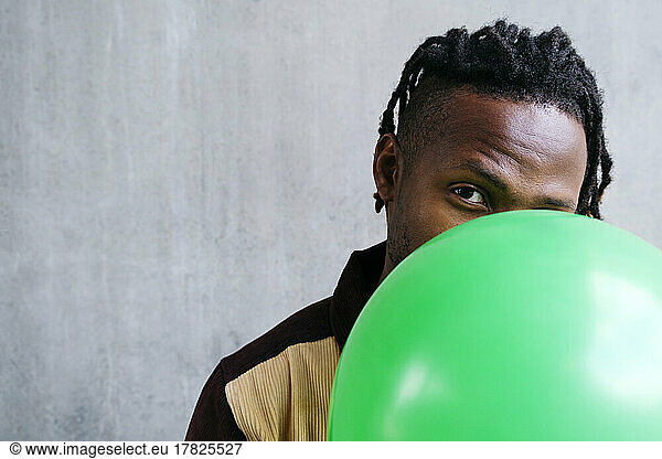Man holding green balloon in front of face