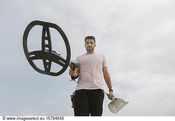 Man holding metal detector  clouds in the background