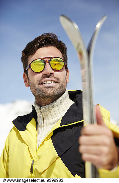 Man holding skis outdoors