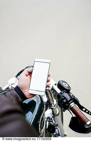 Man holding smartphone while sitting on vintage motorbike