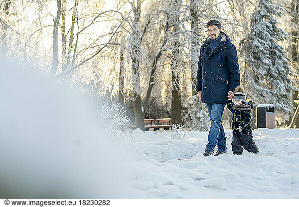 Man holding son's hand walking in winter park