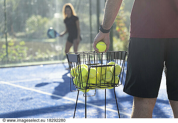 Man holding tennis ball with woman standing in background