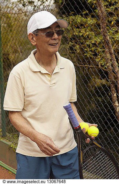 Man holding tennis racket and while standing at court