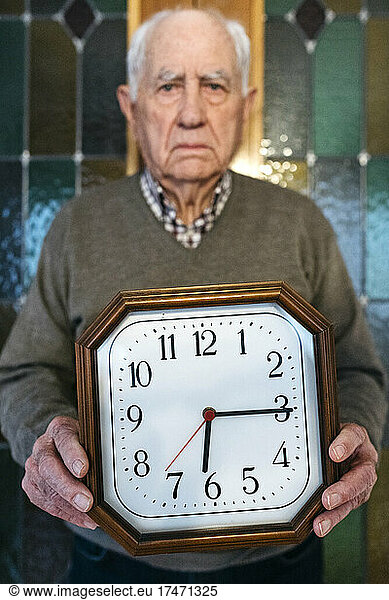 Man holding wall clock at home
