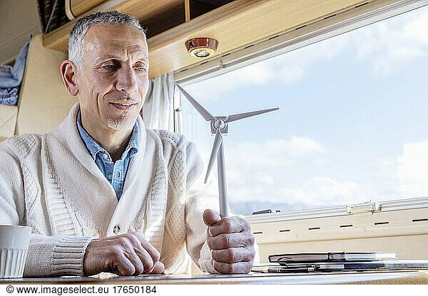 Man holding wind turbine model next to window in camper van