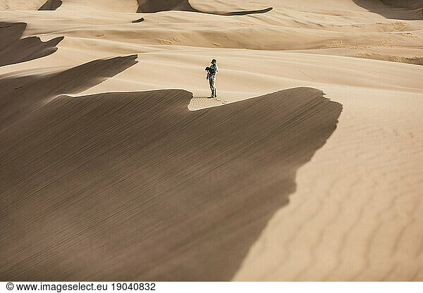 man holds his dog in the windy sand dune ridges of great sand dunes