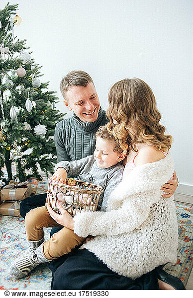 Man hugs his wife  son holds basket with decor for Christmas tree