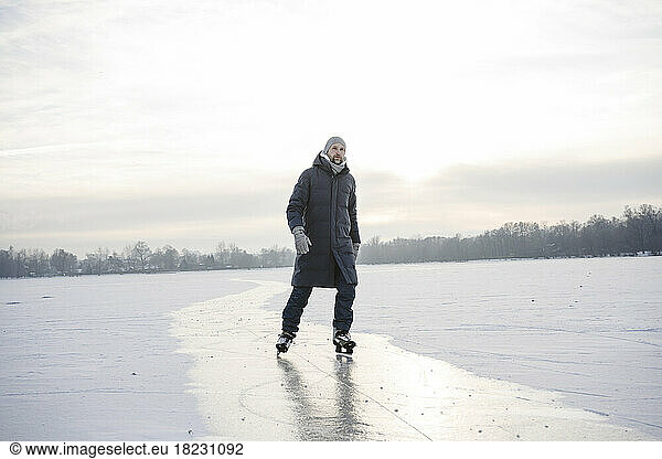 Man ice skating on frozen lake in winter