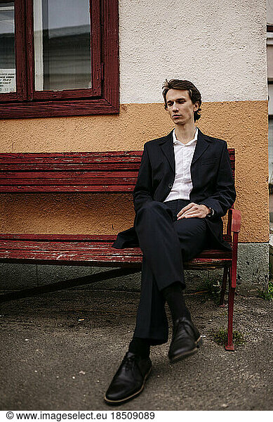 man in a business suit sitting on an old bench