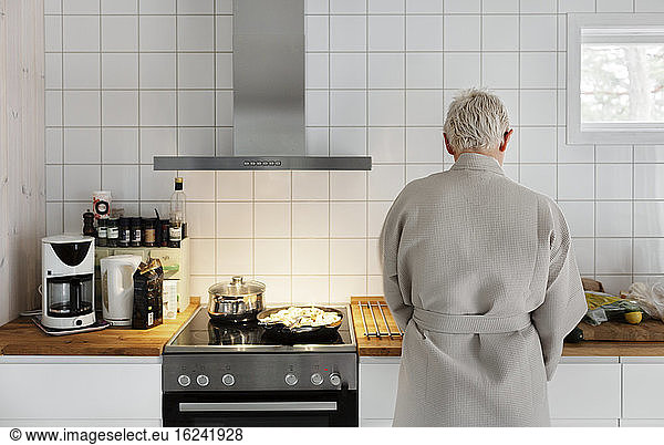Man in bathrobe preparing food