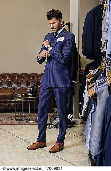 Man in blue pinstripe suit in tailors boutique