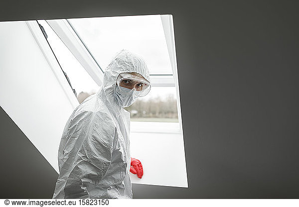 Man in protective clothing  standing at window