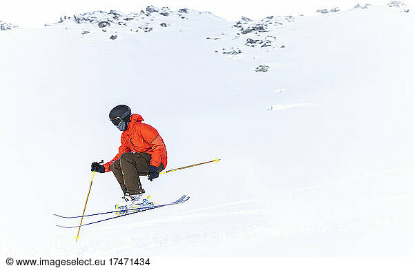 Man in red jacket skiing on snowcapped mountain
