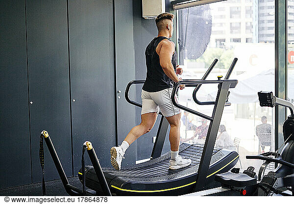 Man in sportswear running on treadmill while training in gym.