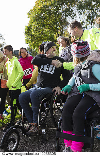 Man in wheelchair shaking hands with runner in crowd at charity race